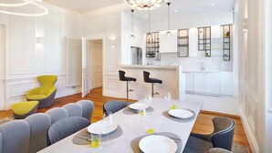 Et moderne spiseområde med et centralt bord dækket til fire personer, omgivet af grå polstrede stole.