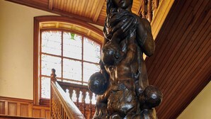 En imponerende trappe med detaljeret træværk og en stor statue foroven.