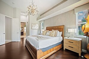 Ein Schlafzimmer mit einem großen Bett, einem Holz-Kopfteil, Nachttischen und einer Chandelier.