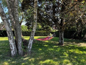 Een hangmat tussen bomen in een grasrijke omgeving.