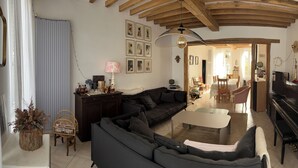 A living room with a sectional sofa, a piano, a dining area, and a staircase leading to another room. - Large family home in Saint-Mards-en-Othe (Saint-Mards-en-Othe)