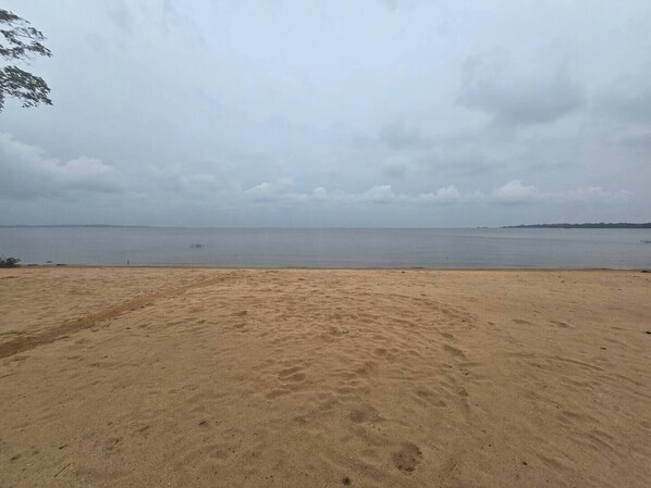 Una playa arenosa con un mar tranquilo y cielo nublado.