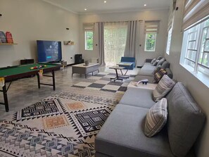 Una sala de estar con mesa de billar, sofá y televisor.