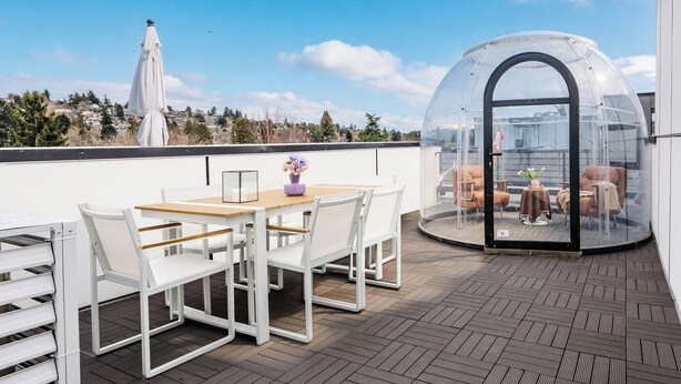 A rooftop terrace with a dining table and chairs, a glass-enclosed seating area, and a view of the cityscape. - New Fremont Designer 3BR TH w/ Rooftop View & King (Seattle)