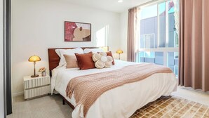 A neatly arranged bedroom with a large bed, two bedside lamps, a window with curtains, and a framed artwork on the wall. - New Fremont Designer 3BR TH w/ Rooftop View & King (Seattle)