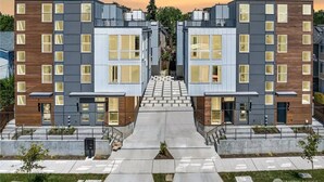 A modern apartment building with a central courtyard, featuring a symmetrical design with multiple floors and large windows. - New Fremont Designer 3BR TH w/ Rooftop View & King (Seattle)