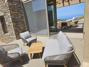 A patio area with wicker furniture, a stone wall, and a view of the sea. - EL-LU 1 Villa with breathtaking 360-degree seaview and a private pool (Kamilari)