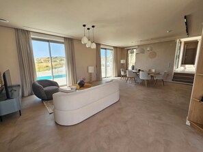 Un salon moderne comprenant un canapé, un coin repas et une vue sur l’extérieur.