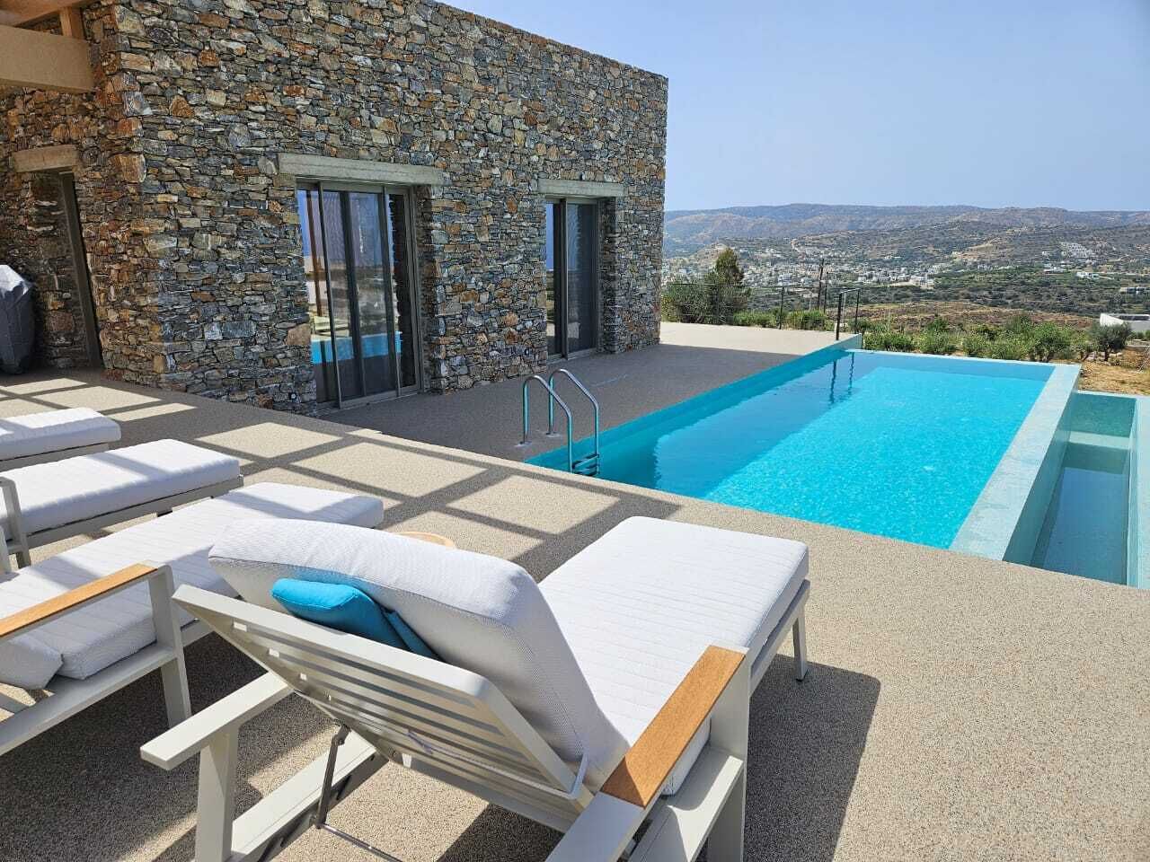 Ein Poolbereich mit Liegestühlen, ein Steinhaus und ein Blick auf die Landschaft.