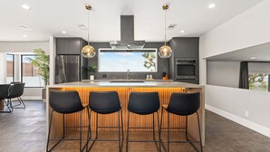 A modern kitchen with a central island, bar stools, and pendant lighting. - Majestic Luxury Retreat | Pool ·Dome · Mini Golf (Joshua Tree)