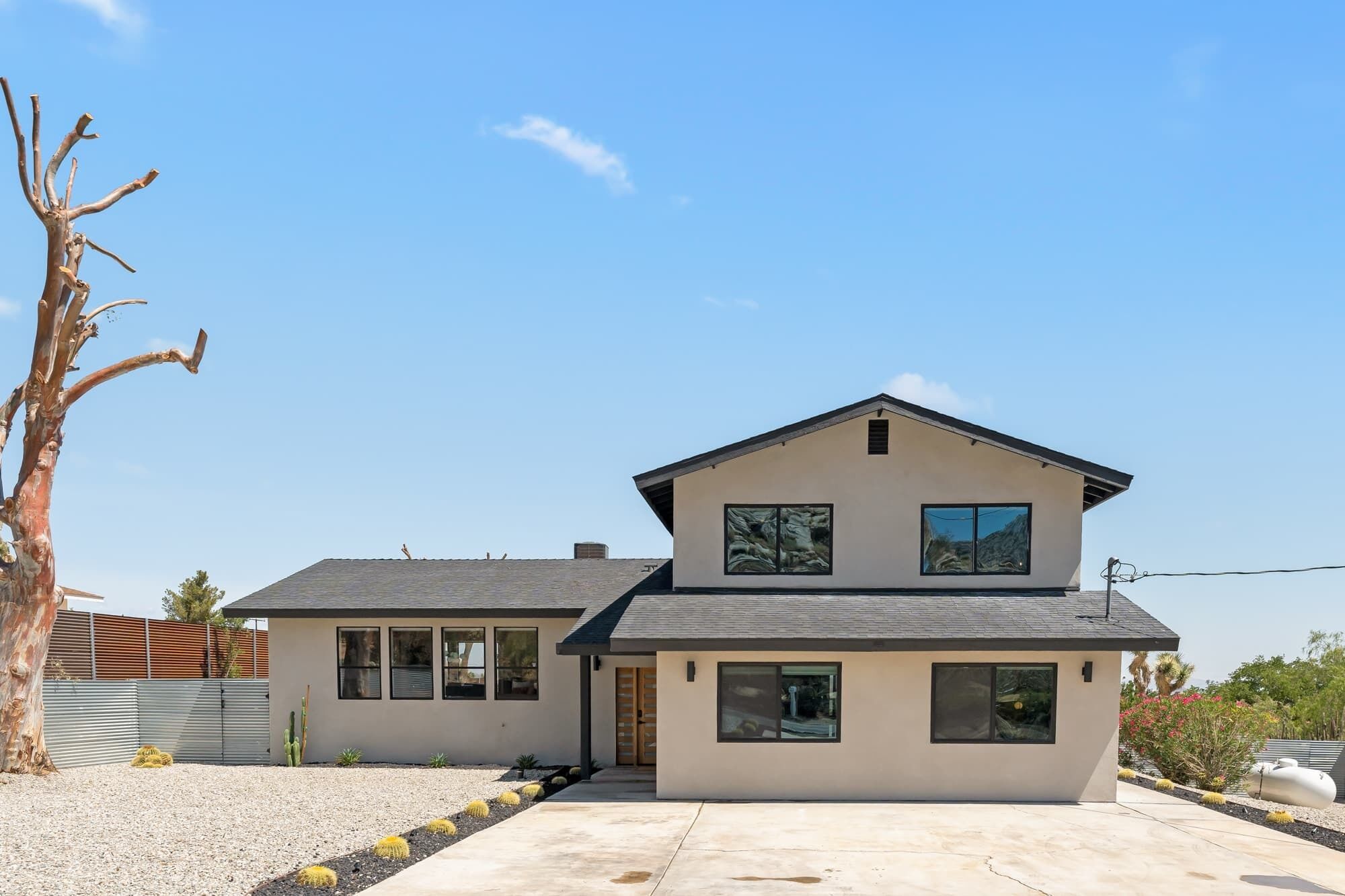 A modern two-story house with a flat roof, large windows, and a small porch.