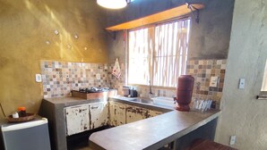 A kitchen with a large island, a refrigerator, a sink, and a window with blinds. - House in Lençóis• 2 suites • garage • Pet friendly (Lençóis)