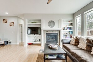 A modern living room with a fireplace, a television, and a bookshelf.
