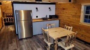 Eine kompakte Küche mit einem Edelstahlkühlschrank, einer Mikrowelle und einem Holzespeisetisch mit Stühlen.