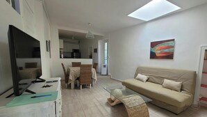 Ein modernes Wohnzimmer mit einer Couch, einem Esstisch und einem Fernseher.