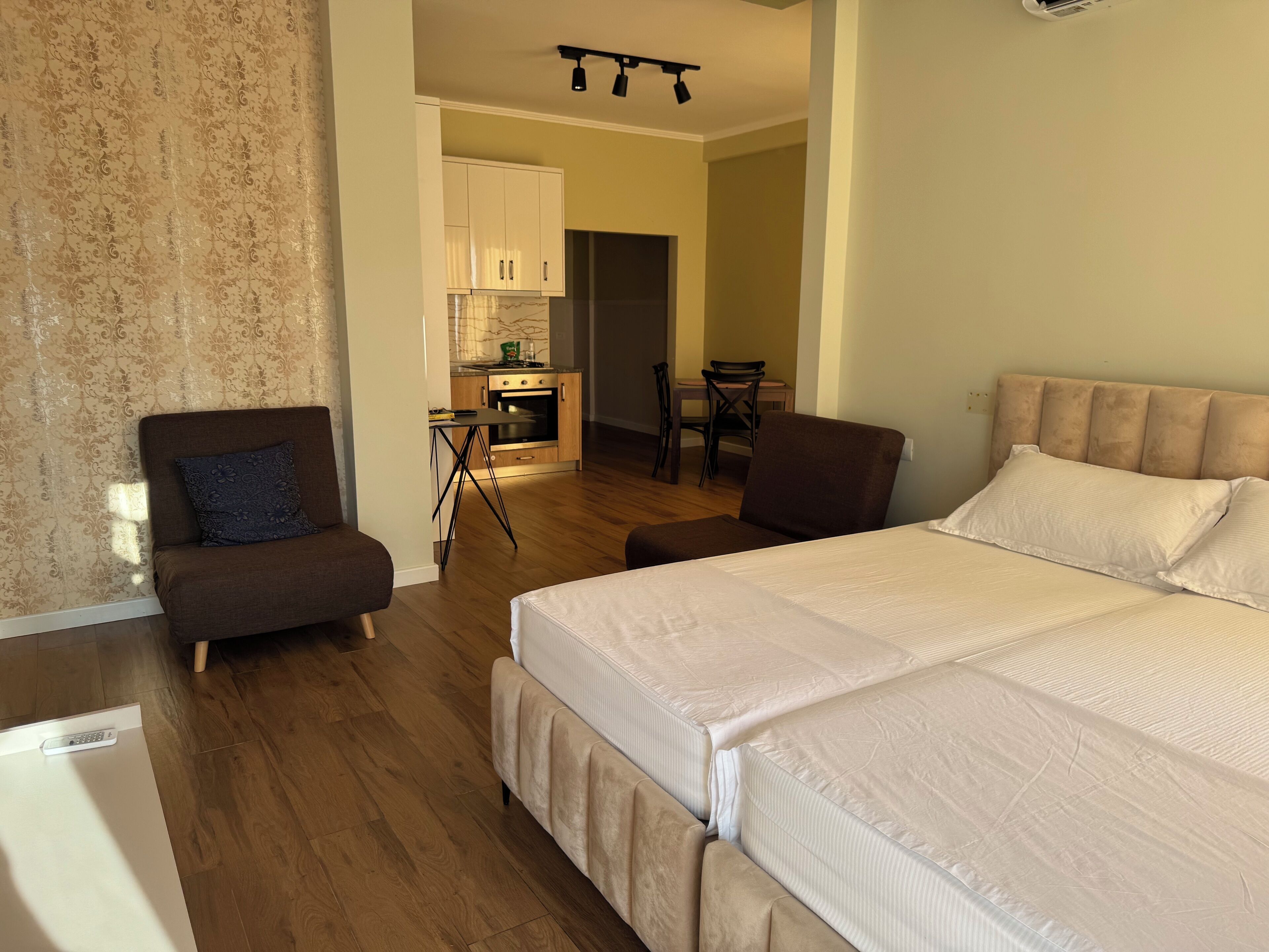 Un dormitorio con una cama grande, un sofá y una kitchenette al fondo.