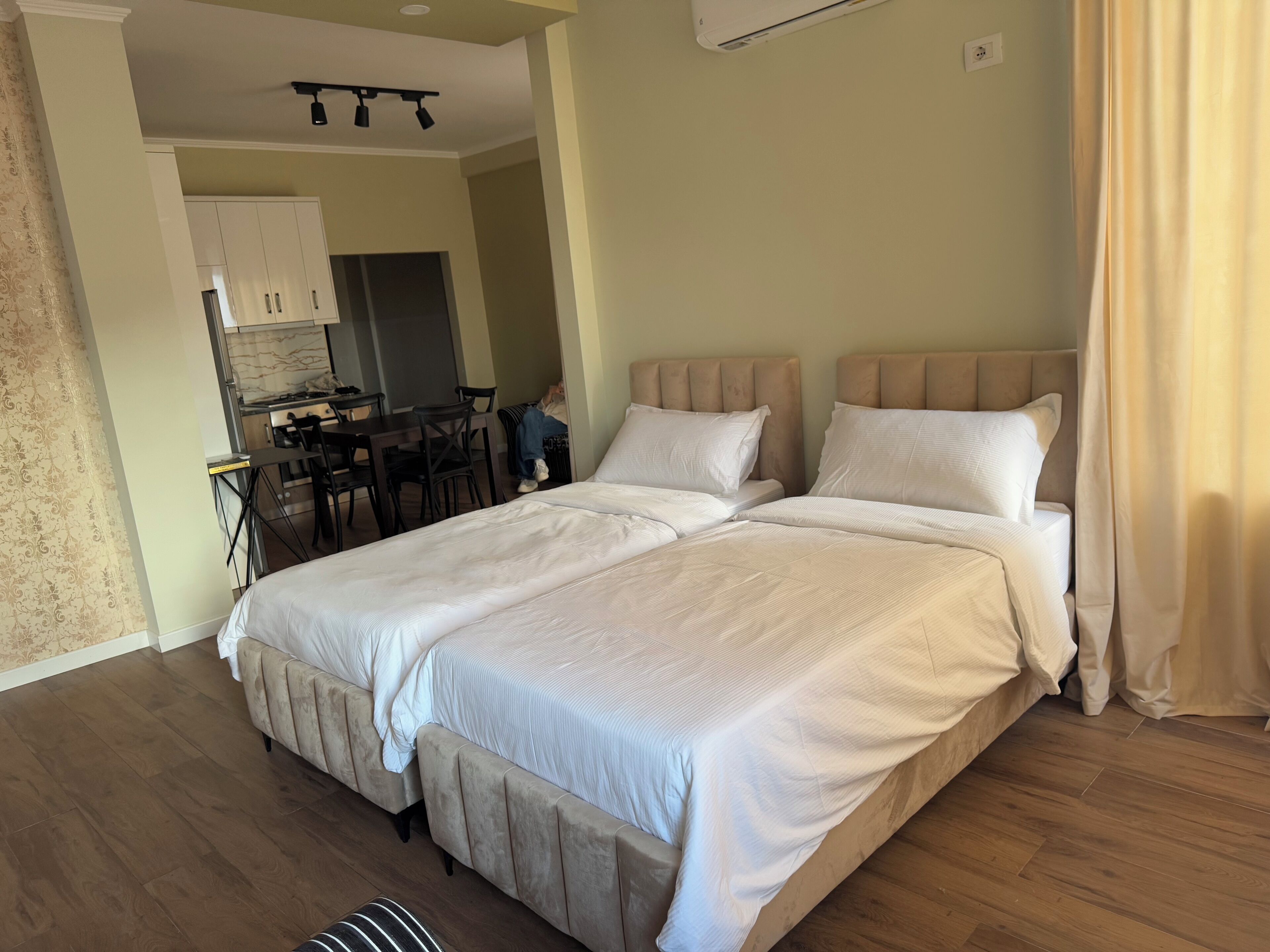 Un lit double avec une tête de lit, un plancher en bois et un coin repas avec une table et des chaises.