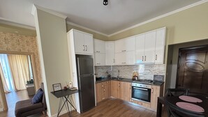 A modern kitchen with white cabinets, a stainless steel refrigerator, and a built-in oven.