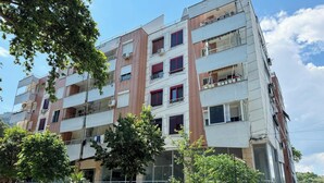 A multi-story residential building with balconies, air conditioning units, and a mix of brick and concrete facades.