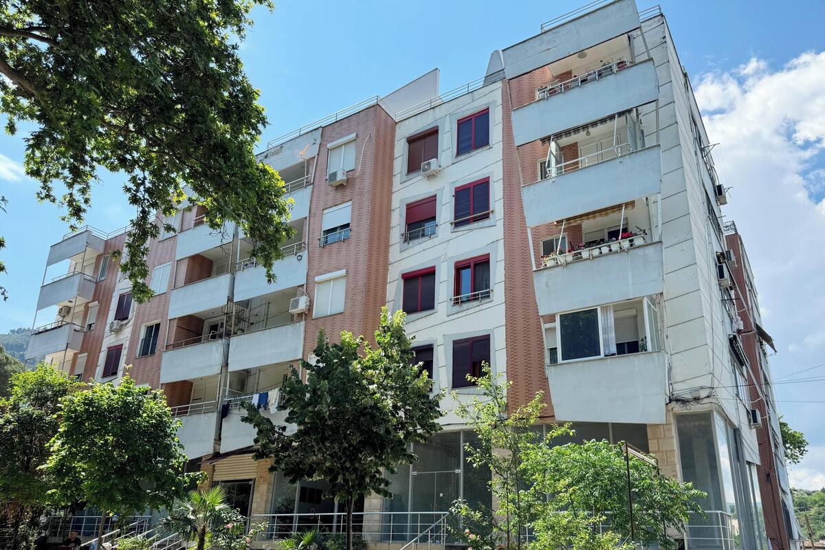 Ein mehrgeschossiges Wohngebäude mit Balkonen, Klimaanlagen und einer Fassade aus Backstein und Beton.