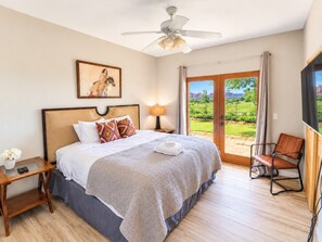 A bedroom with a bed, a nightstand, a chair, a ceiling fan, and a view of the outdoors. - 3 bedroom house with private hot tub (Sedona)