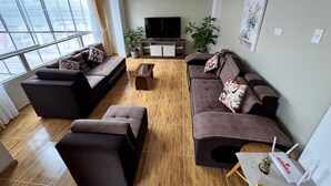 A modern living room with a large sofa set, a coffee table, and a flat-screen TV. - Santa Ana Home, ideal para tu viaje en grupo o familia. (Cusco)