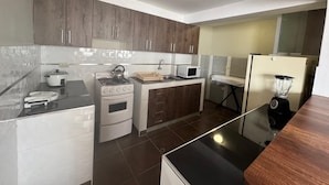 A compact kitchen with a stove, microwave, and blender. - Santa Ana Home, ideal para tu viaje en grupo o familia. (Cusco)