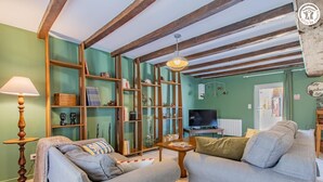 Un salon avec deux canapés gris, une bibliothèque en bois, un téléviseur et une lampe.