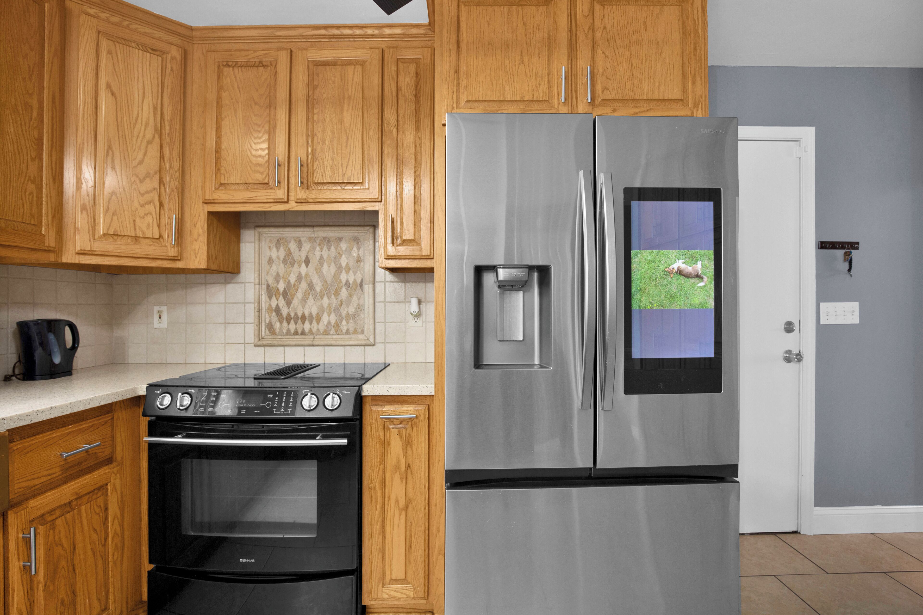 Una cocina con armarios de madera, un refrigerador de acero inoxidable, un horno empotrado y un salpicadero de azulejos.