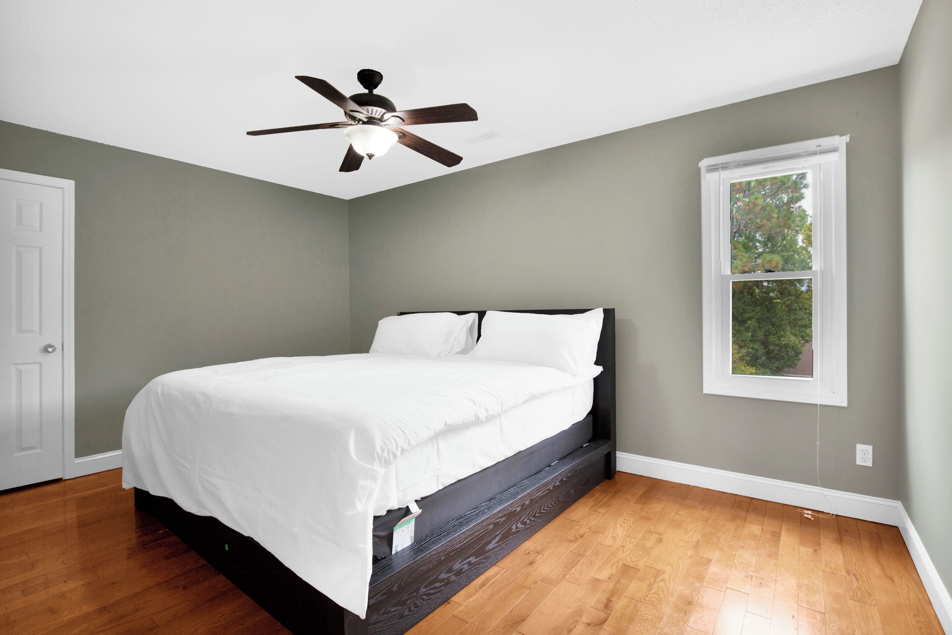 Ein Schlafzimmer mit Bett, Deckenventilator, Fenster und Tür.