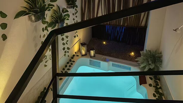 Area piscina interna moderna con barriera in vetro, circondata da pareti decorate con piante e un pannello decorativo in bambù.