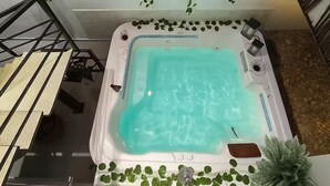 Una vasca idromassaggio con interno blu trasparente, circondata da piante verdi pendenti.