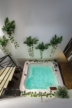 A hot tub with a clear blue interior, surrounded by hanging green plants. - Magic Naranjo House 3BR w/AC & jacuzzi in Laureles (Medellín)
