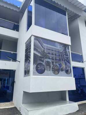 Ein modernes Gebäude mit Glasfassade, mehreren Balkonen und einem zentralen Atrium mit runden Fenstern.