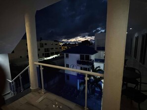 Ein Balkon mit Blick auf Gebäude und einen Sonnenuntergang.