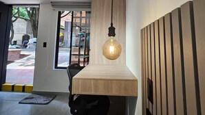 A modern interior with a wooden bench, a hanging light fixture, and a view of the outside through a glass door. - Naranjo Cozy Loft w/AC in Laureles (Medellín)
