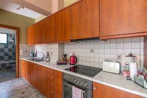 A kitchen with wooden cabinets, a gas stove, a sink, and a toaster. - Fantasia apt by the beach Rethymno Crete (Rethymno)