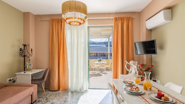 Et hotelværelse med spiseplads, tv og balkon med udsigt.