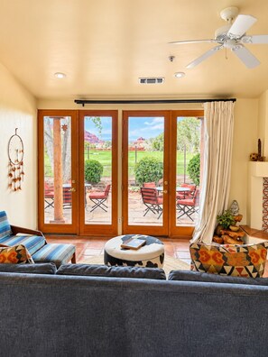 A living room with a sofa, ottoman, and a ceiling fan.