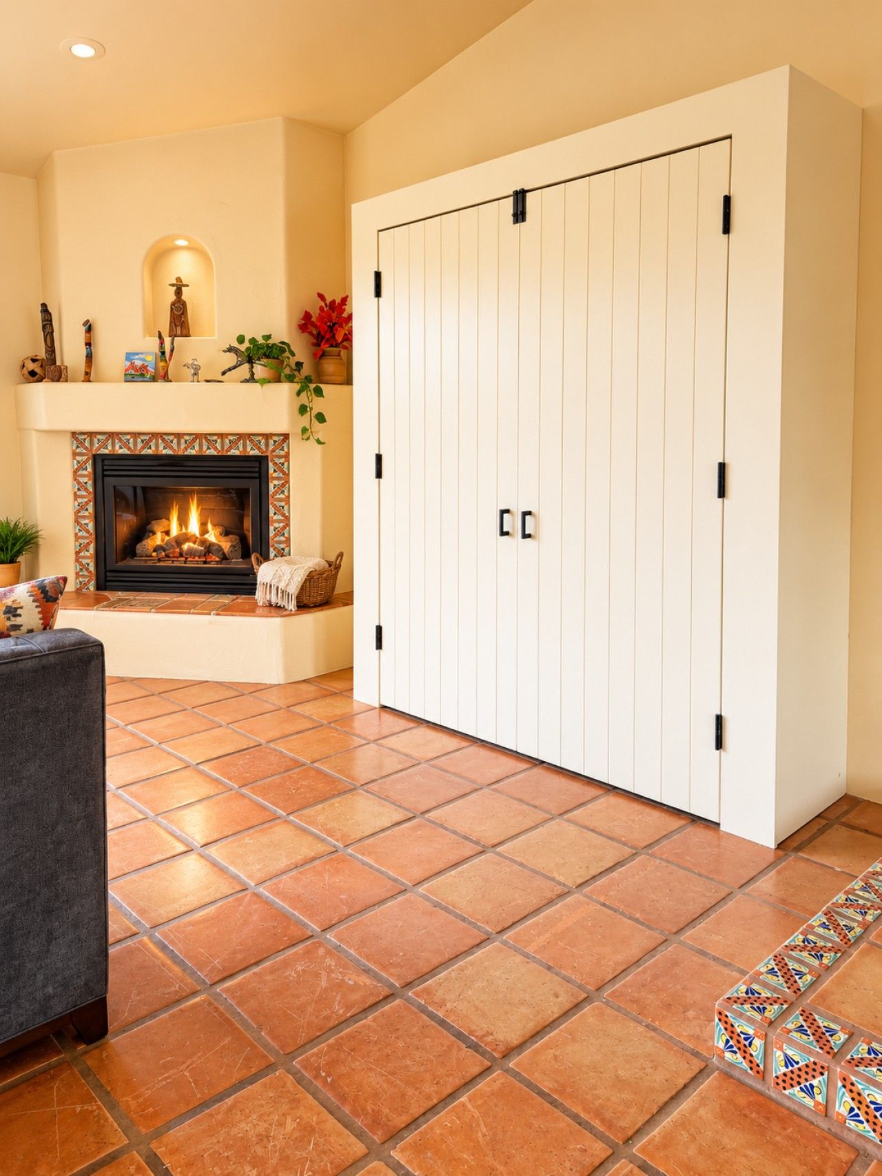 A living room with a fireplace, a large white wardrobe, and a patterned tile floor.