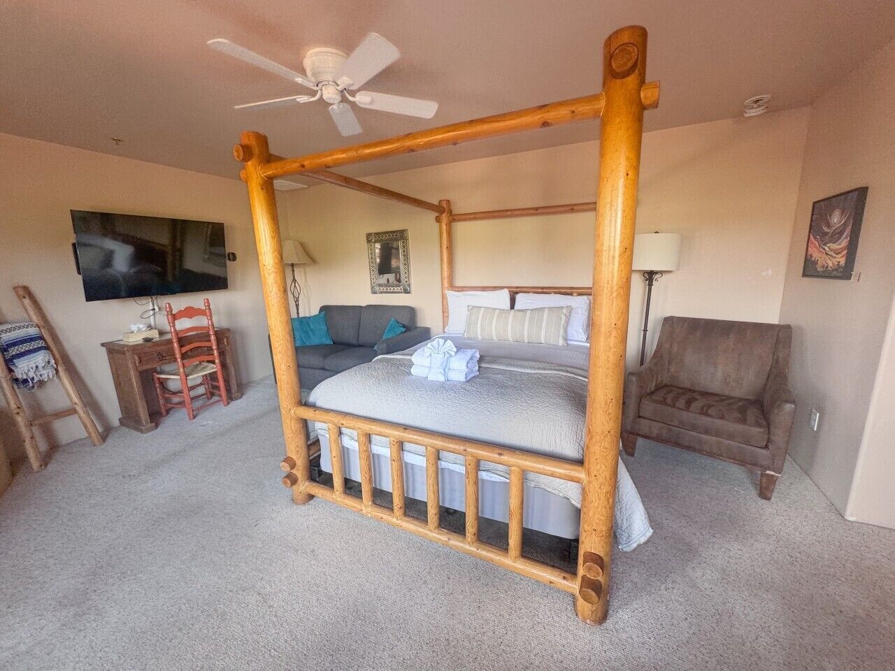 Una habitación con cama con dosel, televisor, escritorio y una silla.