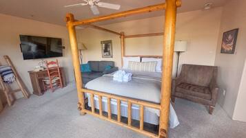 Una habitación con cama con dosel, televisor, escritorio y una silla.