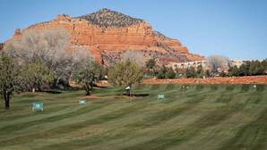 A golf course with numbered holes, a mountain in the background, and trees in the foreground.
