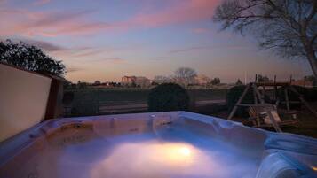 Un jacuzzi con vistas a un atardecer y edificios lejanos.