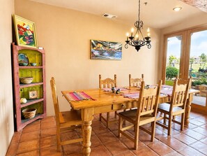 A dining area with a wooden table and chairs, a chandelier, and a view through a glass door. - King studio suite:  hot tub & breakfast (Sedona)