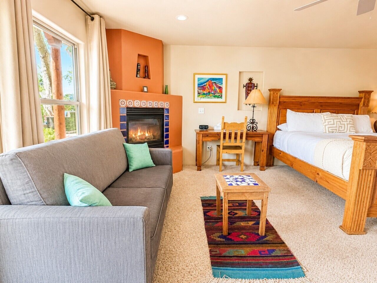 A cozy room with a fireplace, a sofa, a bed, and a small table.