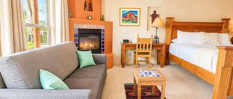 Una habitación acogedora con chimenea, un sofá, una cama y una mesita.