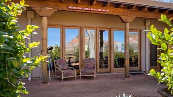 Una pérgola de madera con un letrero que dice "Adobe Hacienda Bed & Breakfast" y dos sillas con diseños debajo.