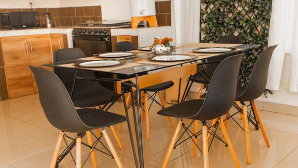 A modern kitchen with a dining table set for four, surrounded by black chairs with wooden legs. - Casa con la mejor ubicación a minutos de Xetulul (Santa Cruz Muluá)
