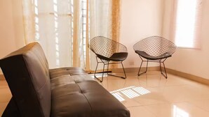 A modern room with a leather sofa and two wireframe chairs. - Casa con la mejor ubicación a minutos de Xetulul (Santa Cruz Muluá)